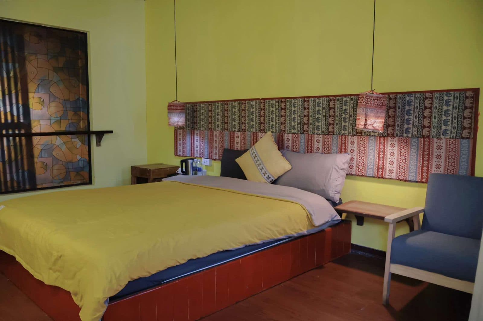 Phòng Cozy Standard tường vàng, một giường lớn và đầu giường thổ cẩm.